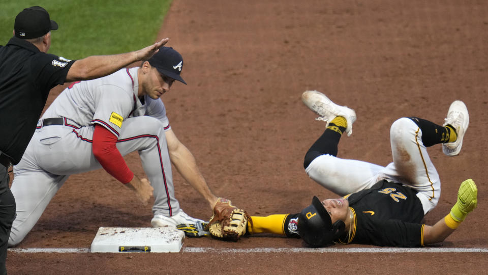 Pittsburgh Pirates' Endy Rodriguez, right, dives safely back to first as Atlanta Braves first baseman Matt Olson, center, applies a late tag and umpire Jeremy Riggs, left, makes the call during the third inning of a baseball game in Pittsburgh, Monday, Aug. 7, 2023. (AP Photo/Gene J. Puskar)