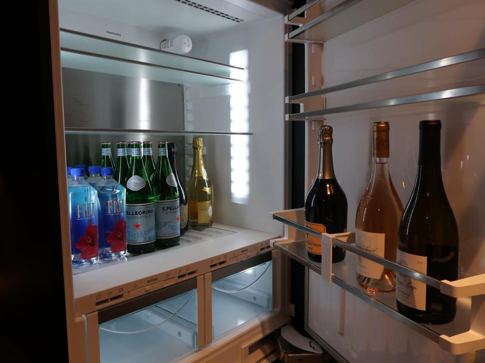 A fridge filled with wine, champagne, sparkling water, and still water.