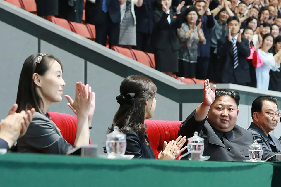 FILE - In this June 3, 2019, file photo provided by the North Korean government, North Korean leader Kim Jong Un, second right, waves with his wife Ri Sol Ju, center, during the grand gymnastics and artistic performance at the May Day Stadium in Pyongyang. The woman next to Ri Sol Ju appears to be Kim's sister, Kim Yo Jong, who state media said attended the performance. The coronavirus is the biggest reason for North Korea’s decision not to come to Tokyo. The nation has shut its borders tighter than normal, worried that its fragile health care system and rickety economy could not withstand a major outbreak. That, in turn, could put the ruling Kim family in danger. (Korean Central News Agency/Korea News Service via AP, File)