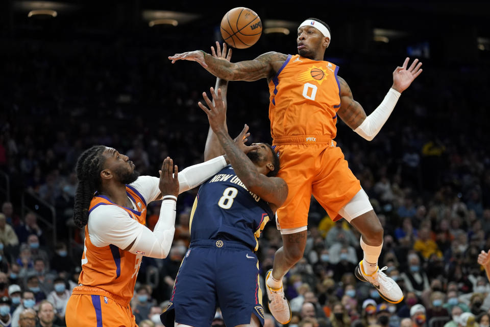 Phoenix Suns forward Torrey Craig (0) fouls New Orleans Pelicans forward Naji Marshall (8) as Phoenix Suns forward Jae Crowder defends during the first half of an NBA basketball game, Friday, Feb. 25, 2022, in Phoenix. (AP Photo/Matt York)