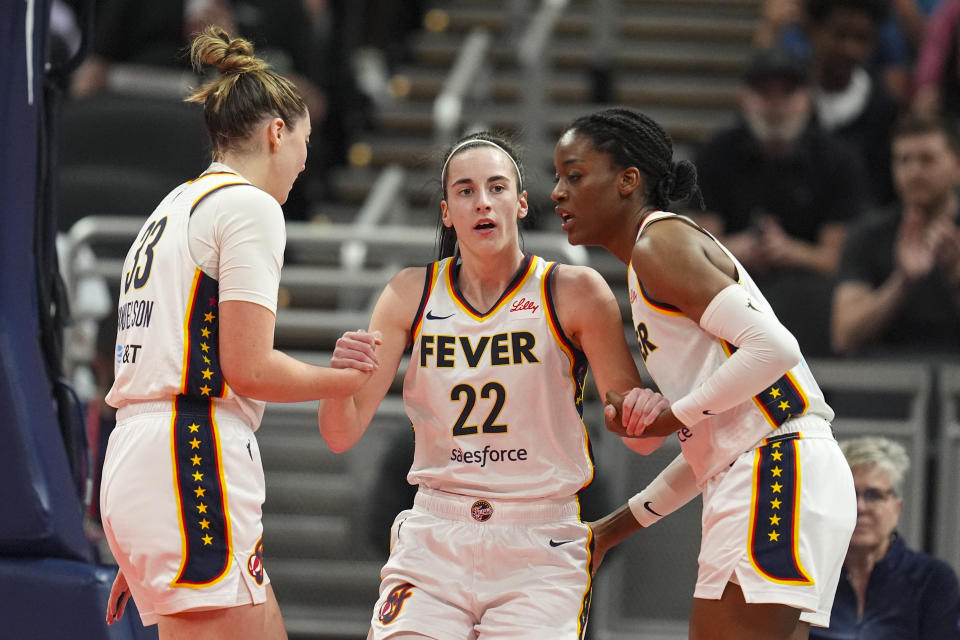 Caitlin Clark (22), del Fever de Indiana, es asistida para ponerse de pie por sus compañeras de equipo, Katie Lou Samuelson (33) y Temi Fagbenle (14) en la primera mitad del juego de baloncesto de la WNBA en contra del Sun de Connecticut, el lunes 20 de mayo de 2024, en Indianápolis. (AP Foto/Michael Conroy)