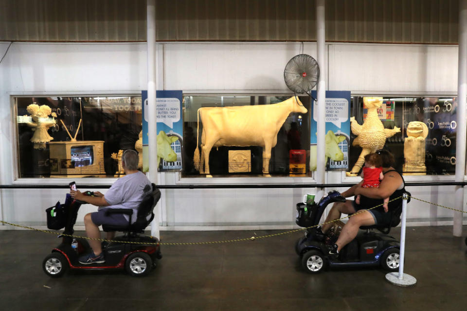 People in scooters in front of the butter cow