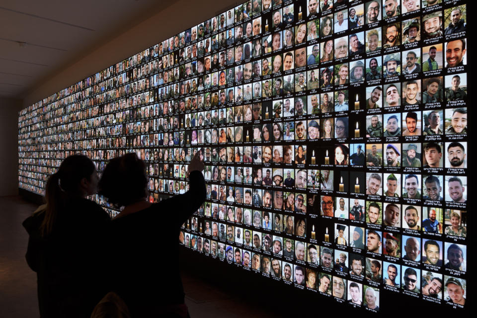 Visitantes observan fotos de israelíes asesinados durante el ataque de milicianos de Hamás el 7 de octubre y los que han muerto en la guerra entre Israel y Hamás en la Franja de Gaza, mostradas en una pantalla gigante en la Biblioteca Nacional, el domingo 28 de enero de 2024, en Jerusalén. (AP Foto/Leo Correa)