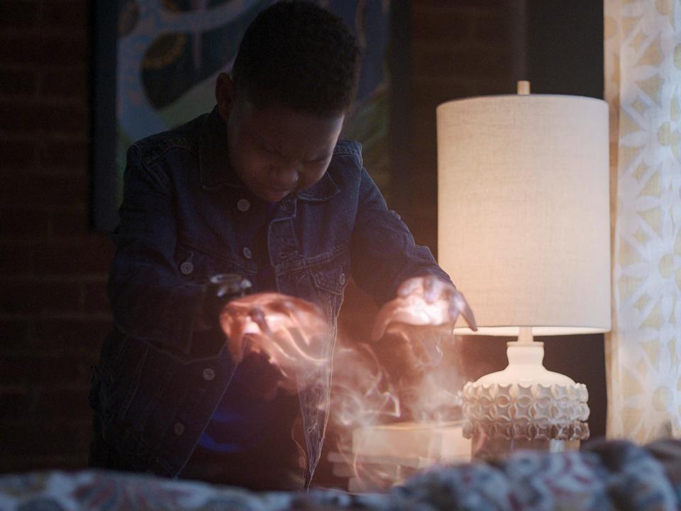 Ja'Siah Young in scene with orange light shooting from his hands toward woman in bed in "Raising Dion"