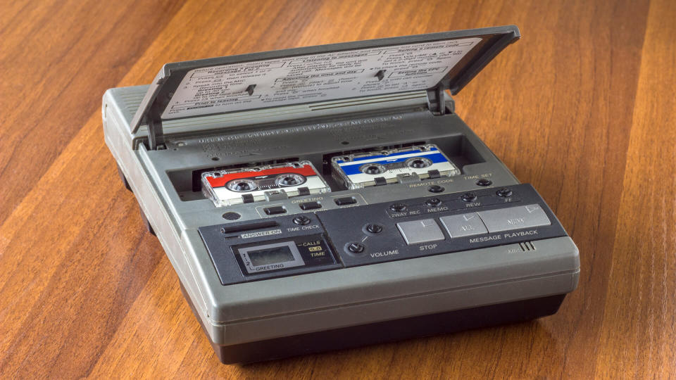 old vintage answering machine with two small tape cassettes on a wooden table surface - Image.