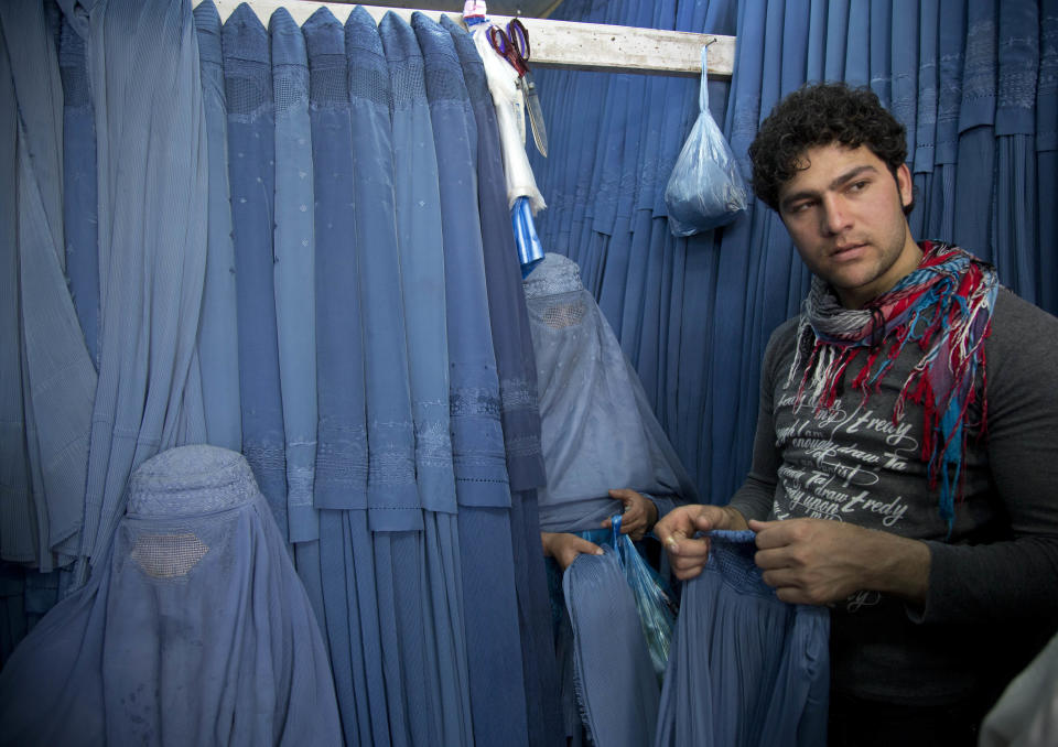 In this Thursday, April 11, 2013 photo, Nazar, right, a salesman at a burqa store, helps women to choose a burqa at a shop in the old town of Kabul, Afghanistan. Despite advances in women’s rights, Afghanistan remains a deeply conservative country and most women continue to wear the Burqa. But tradesmen say times are changing in Kabul at least, with demand for burqas declining as young women going to school and taking office jobs refuse to wear the cumbersome garments. (AP Photo/Anja Niedringhaus)