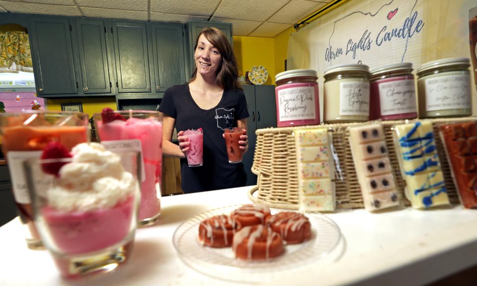 Kimberly Ochsenbein, owner of Akron Lights Candle Co., poses for a portrait with some of her unique soy candles in the form of iced coffee, cinnamon rolls, chocolate bars and more, Tuesday, Feb. 7, 2023, in Akron, Ohio.