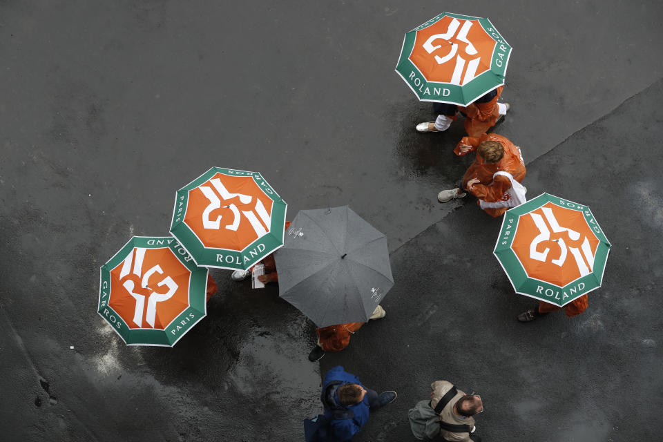 Spectators with umbrellas stroll as rain delayed the start of quarterfinal matches of the French Open tennis tournament at the Roland Garros stadium in Paris, Wednesday, June 5, 2019. (AP Photo/Pavel Golovkin)