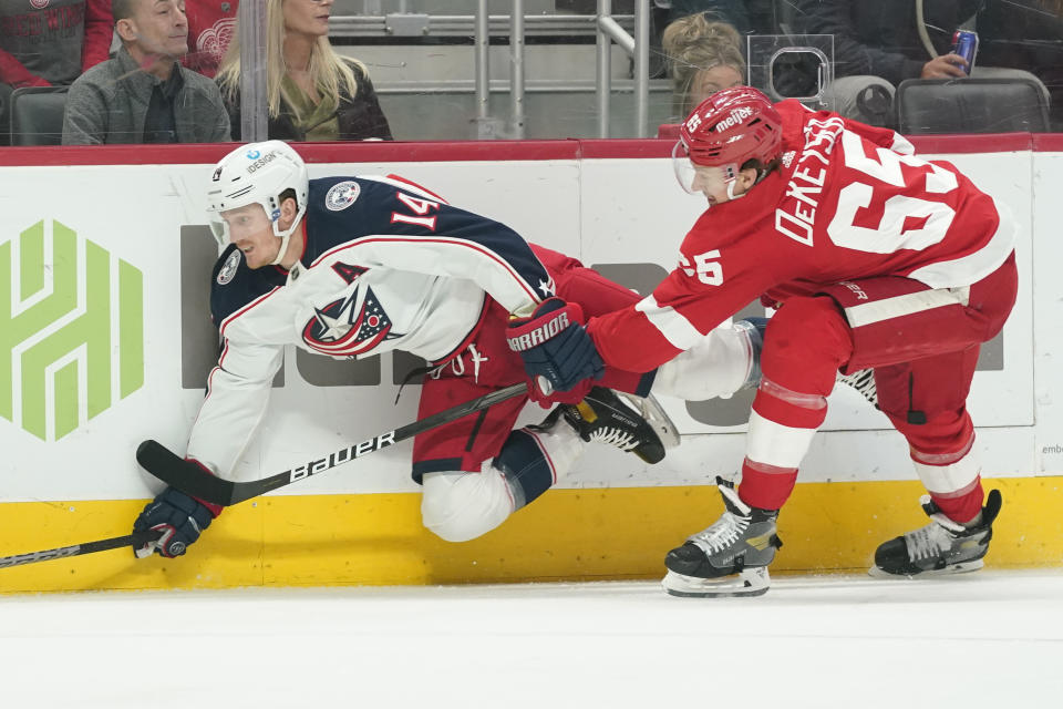 Detroit Red Wings defenseman Danny DeKeyser (65) checks Columbus Blue Jackets center Gustav Nyquist (14) in the first period of an NHL hockey game Saturday, April 9, 2022, in Detroit. (AP Photo/Paul Sancya)