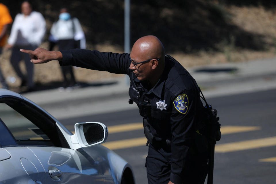 A police officer directs traffic at a road closure after a shooting near a school in Oakland, California, U.S. September 28, 2022. REUTERS/Nathan Frandino