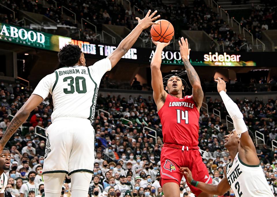 Dec 1, 2021; East Lansing, Michigan, USA;  Louisville Cardinals guard Dre Davis (14) shoots while Michigan State Spartans forward Marcus Bingham Jr. (30) and guard Tyson Walker (2) defend at Jack Breslin Student Events Center. Mandatory Credit: Dale Young-USA TODAY Sports