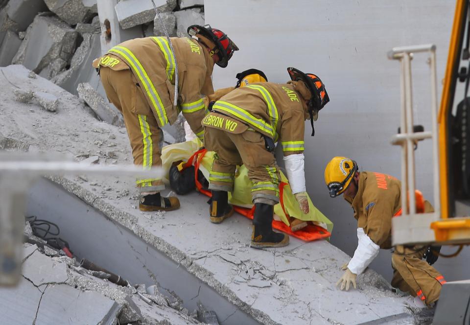 MIAMI, FL - OCTOBER 10: Miami-Dade Rescue workers pull a body out of the rubble of a four-story parking garage that was under construction and collapsed at the Miami Dade College’s West Campus on October 10, 2012 in Doral, Florida. Early reports indicate that one person was killed, at least seven people injured and an unknown number of people may be buried in the rubble. (Photo by Joe Raedle/Getty Images)
