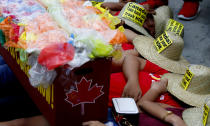 With a mock container loaded with garbage, environmentalists stage a die-in protest outside the Canadian Embassy to demand the Canadian government to speed up the removal of several containers of garbage that were shipped to the country Tuesday, May 21, 2019, in Manila, Philippines. The Philippines recalled its ambassador and consuls in Canada last week over Ottawa's failure to comply with a deadline to take back 69 containers of garbage that Filipino officials say were illegally shipped to the Philippines years ago. (AP Photo/Bullit Marquez)