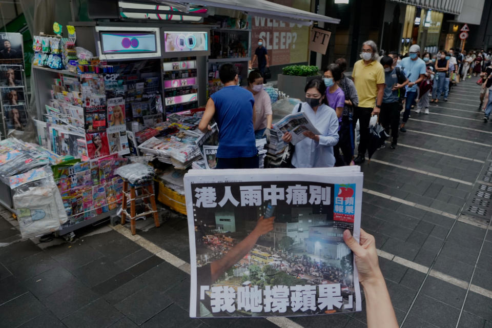 FILE - In this Thursday, June 24, 2021 file photo, a woman tries to take a picture of last issue of Apple Daily in front of a newspaper booth where people queue up to buy the newspaper at a downtown street in Hong Kong. The coronavirus pandemic has upended life around the globe, but it has hasn’t stopped the spread of authoritarianism and extremism. Some researchers believe it may even have accelerated it, but curbing individual freedoms and boosting the reach of the state. Since COVID-19 hit, Hungary has banned children from being told about homosexuality. China shut Hong Kong’s last pro-democracy newspaper. Brazil’s president has extolled dictatorship. Belarus has hijacked a passenger plane. A Cambodian human rights lawyer calls the pandemic “a dictator's dream opportunity.” But there are also resistance movements, as protesters from Hungary to Brazil take to the streets to defend democracy. (AP Photo/Vincent Yu, File)