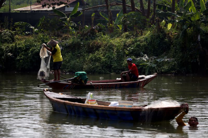 Fishermen are seen on wooden boats as they look for fish at Cisadane river in Tangerang