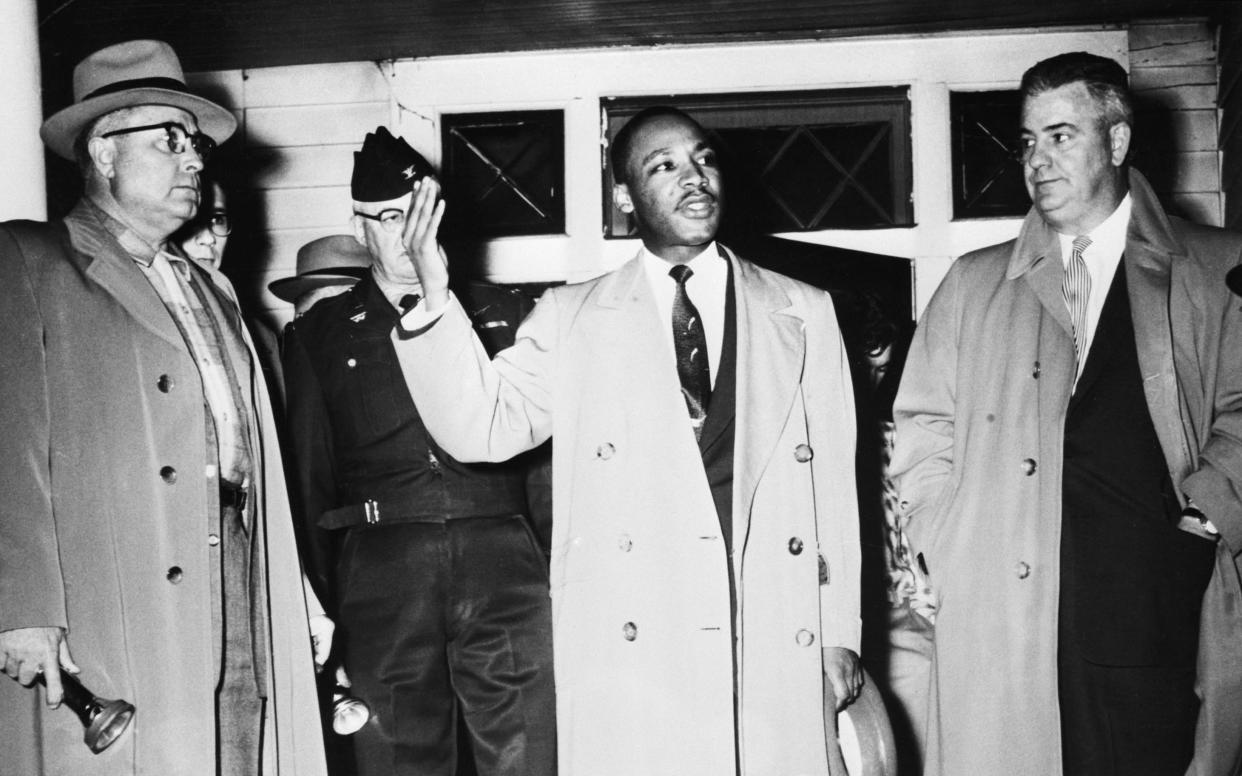Martin Luther King Jr. urges calm from the porch of his home, which was damaged by a bomb during a boycott of the Montgomery, Ala.., bus system to protect segregation in 1956. With him, left to right, are: Fire Chief R.L. Lampley; Mayor W.A. Gayle (in uniform) and City Police Commissioner Clyde Sellers. (Photo: Bettmann/Getty Images)