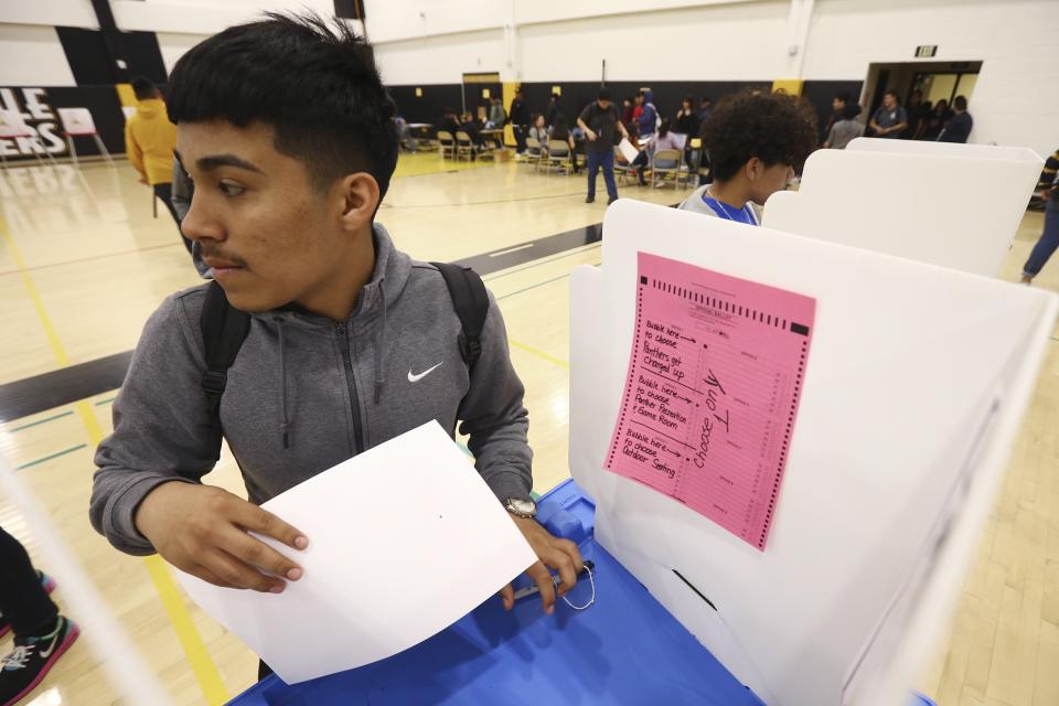 In this March 5, 2020, photo after filling out his ballot, Jesus Caldera joins other students as they participate in their own Democratic presidential preference election and voter registration drive at Maryvale High School in Phoenix. At the school hundreds of students who will turn 18 before Election Day were registered to vote. (AP Photo/Ross D. Franklin)