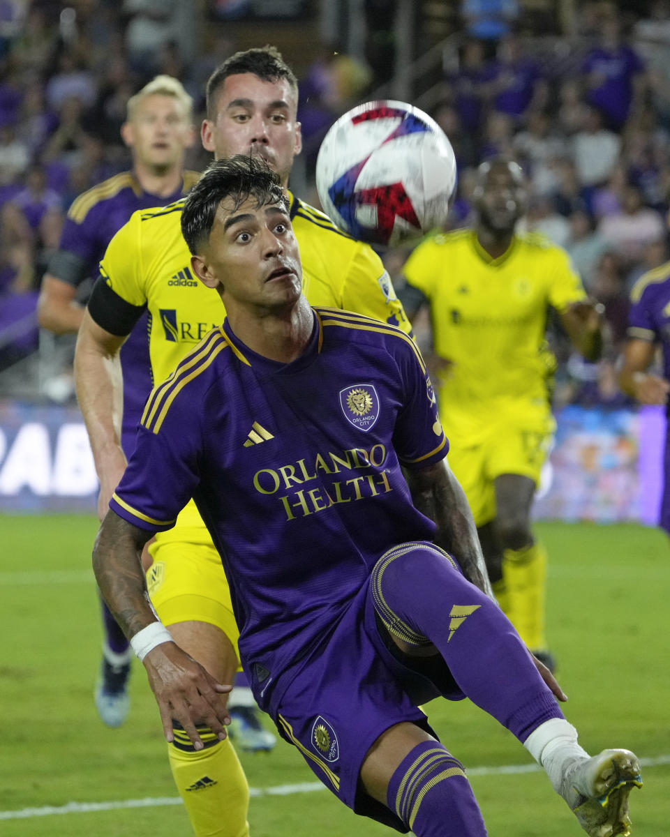 Orlando City's Facundo Torres, front, tries to control a pass in front of Nashville SC's Daniel Lovitz during the second half of an MLS soccer match, Saturday, April 1, 2023, in Orlando, Fla. (AP Photo/John Raoux)