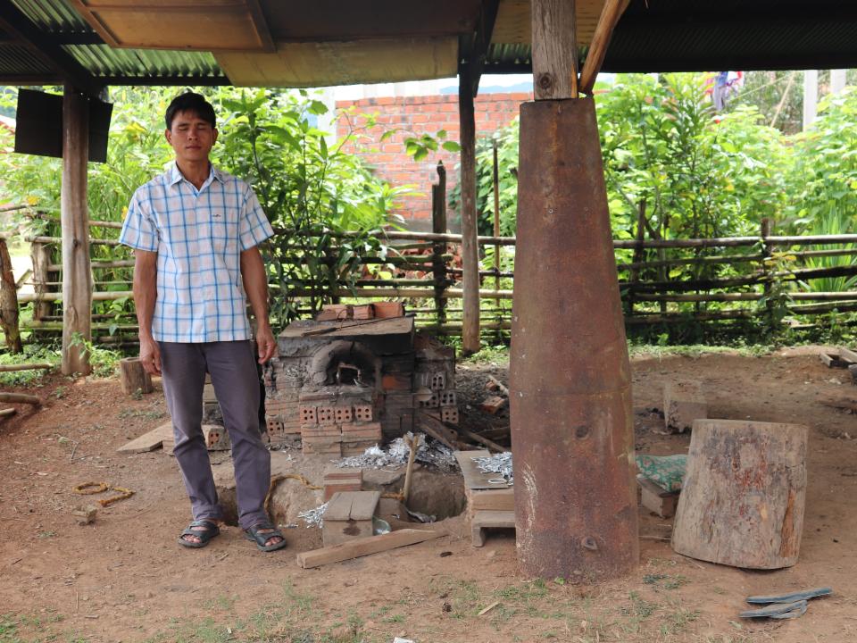 Sone standing under a shelter which is supported by a pillar made from the outer casing of an unexploded bomb