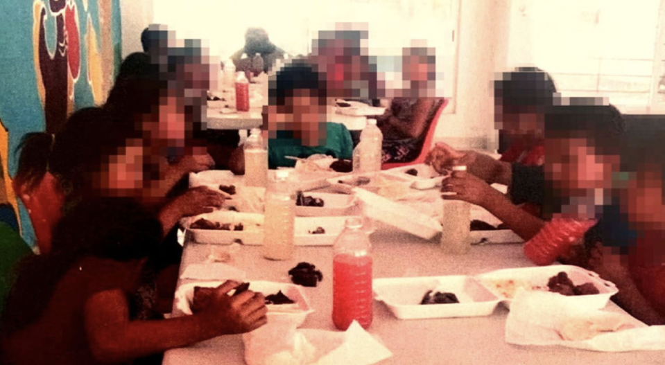 Twenty-three kids are seen at a table.