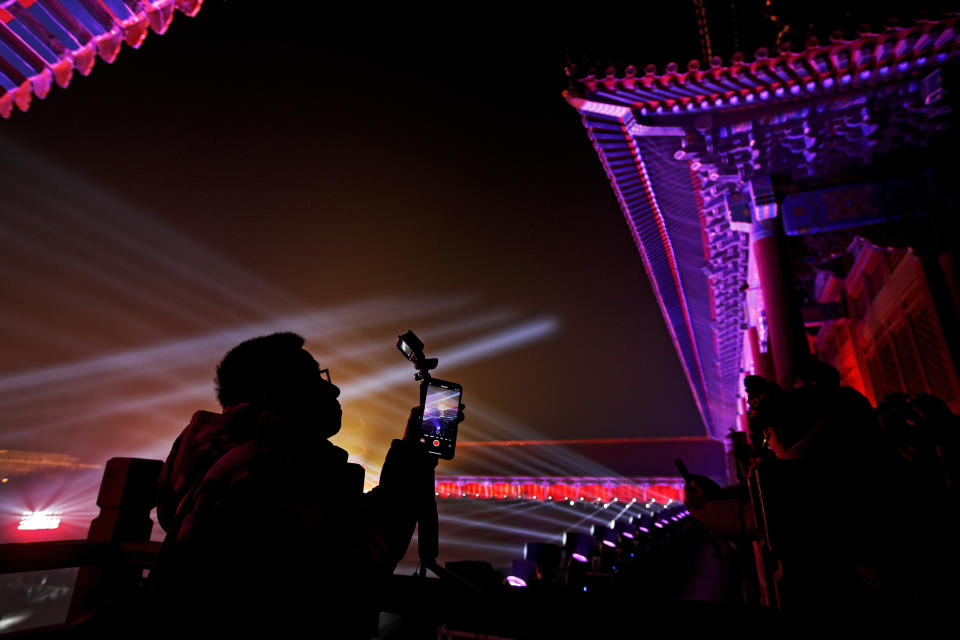 In this Tuesday, Feb. 19, 2019, photo, visitors take photos of the Forbidden City illuminated with lights for the Lantern Festival in Beijing. China lit up the Forbidden City on Tuesday night, marking the end of 15 days of lunar new year celebrations. It was not a Lantern Festival the last emperor, who abdicated in 1912, would have recognized. There were lanterns, but those lucky enough to snag tickets saw a laser light show and historic buildings bathed in colorful lights. Others watched from outside the vast walled compound in Beijing, from where Ming and Qing dynasty emperors ruled for five centuries. (AP Photo/Andy Wong)