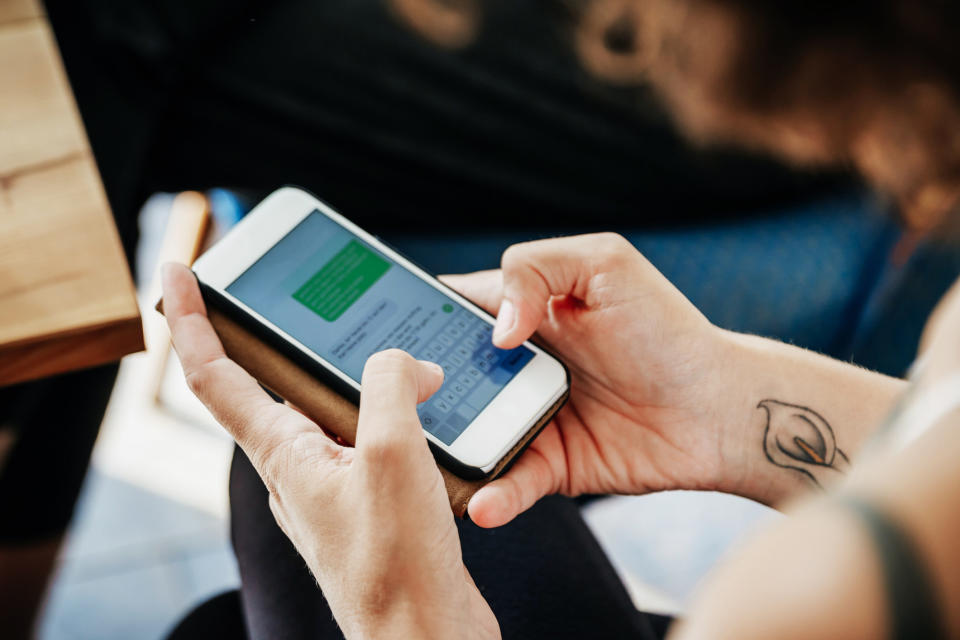 Close-up of someone's hands texting and green text bubble on the screen