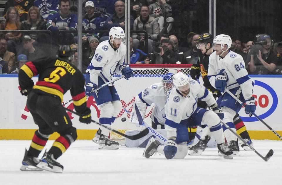 Vancouver Canucks' Brock Boeser (6) scores a goal against Tampa Bay Lightning goalie Andrei Vasilevskiy (88) as Nicklaus Perbix (48), Tanner Jeannot (84) and Luke Glendening (11) defend during the second period of an NHL hockey game in Vancouver, B.C., on Tuesday, Dec. 12, 2023. (Darryl Dyck/The Canadian Press via AP)