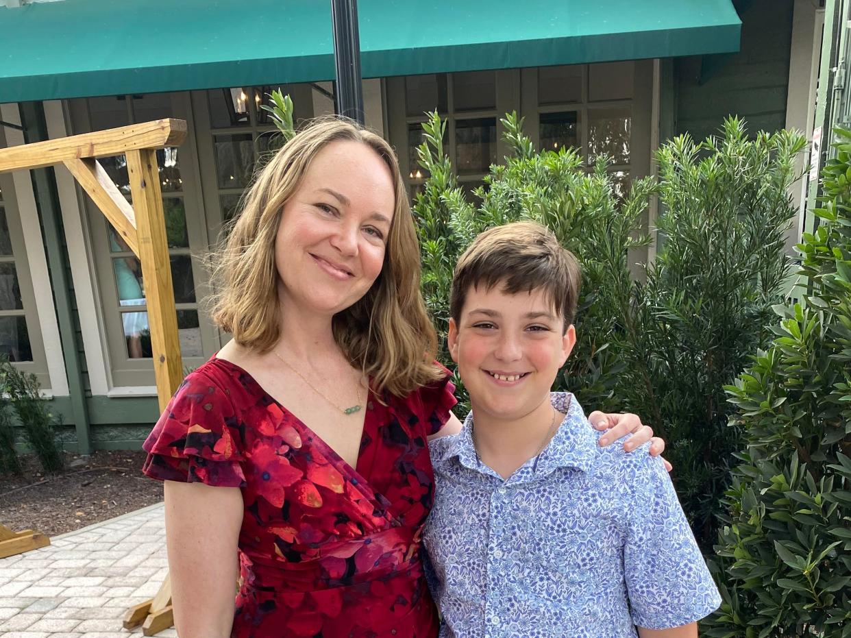 Ashley Archambault and her son standing on a paved walkway and smiling.