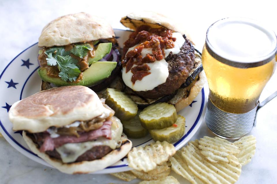 In this image taken on June 10, 2013, clockwise from top right, The Eggplant Parm, The New Yorker and The Thai, burgers are shown on a plate in Concord, N.H. (AP Photo/Matthew Mead)