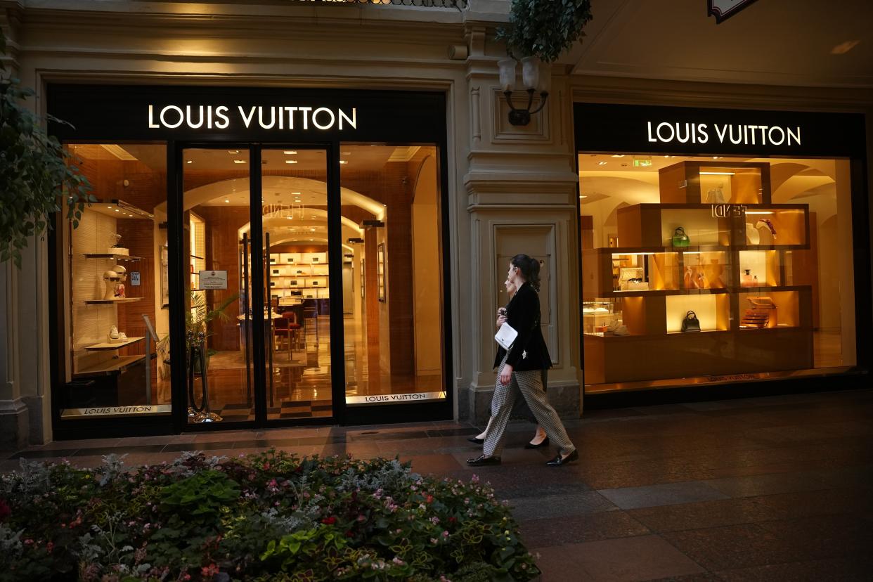 Two women walk past a Louis Voutton boutique closed due to sanctions in the GUM department store in Moscow, Russia, Tuesday, Aug. 9, 2022. Often, it's hard to tell when stores are closed. At the famous GUM department store lined with shops in Red Square, most of the closed storefronts still had the lights on and a clerk or guard inside. (AP Photo/Alexander Zemlianichenko)