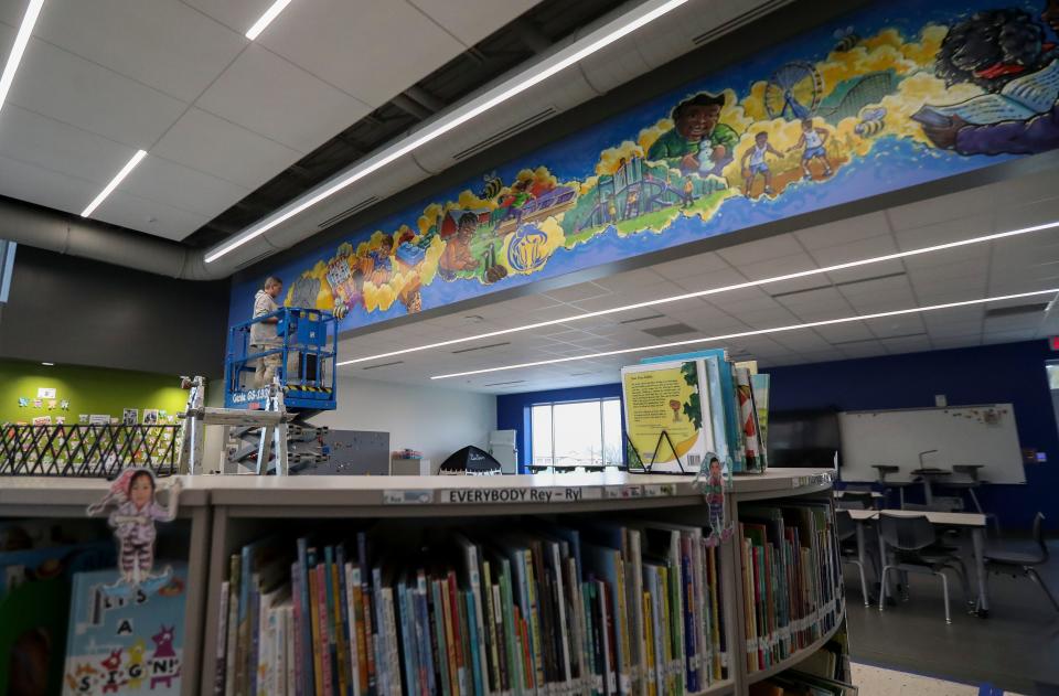 Artist Greg Preslicka works on a mural in the library on  April 18 at Martin Elementary in Green Bay.