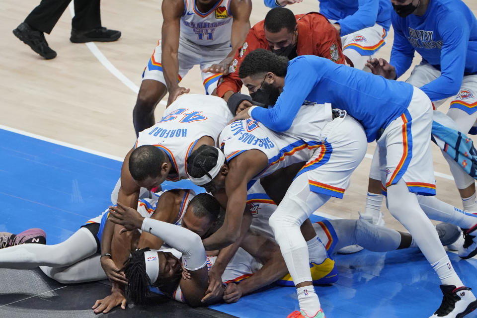 Oklahoma City Thunder forward Luguentz Dort, bottom, is mobbed by teammates after hitting the game-winning shot in an NBA basketball game against the San Antonio Spurs, Wednesday, Feb. 24, 2021, in Oklahoma City. (AP Photo/Sue Ogrocki)