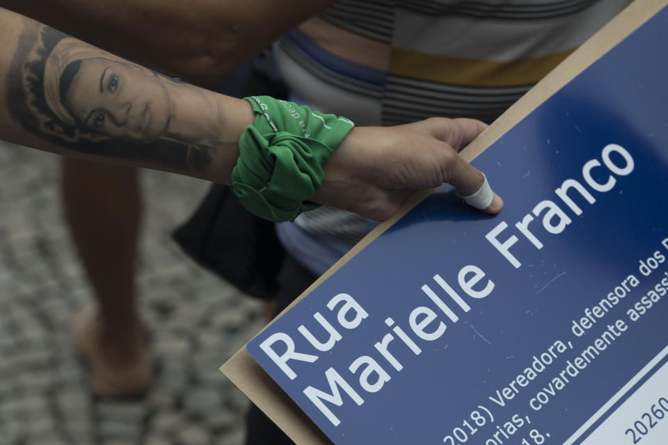 The widow of slain councilwoman Marielle Franco has a tattoo of Franco on her arm, during a demonstration marking the 7th month since her wife's murder in Rio de Janeiro, Brazil, Sunday, Oct. 14, 2018. Franco supporters distributed a thousand street signs in memory of her after a video on social media showed one being destroyed by two politicians with the right wing Social Liberal Party. (AP Photo/Leo Correa)