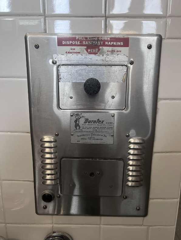 Sanitary napkin disposal unit on a tiled wall with operational instructions