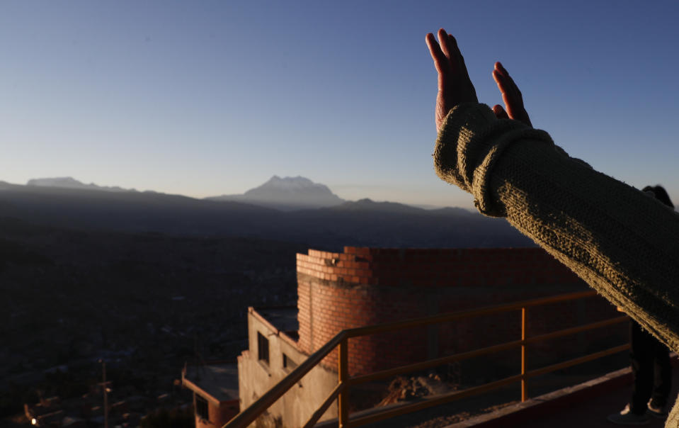 Una mujer levanta las manos ante los primeros rayos de sol durante un ritual de año nuevo en el Mirador Jach'a Apacheta de Munaypata, en La Paz, Bolivia, el domingo 21 de junio de 2020. Las comunidades indígenas aymaras celebran el Año Nuevo Andino 5.528 en medio de la pandemia del coronavirus. (Foto AP/Juan Karita)