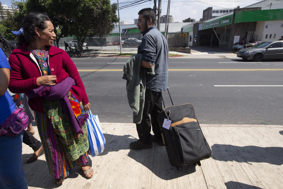 A woman looks over at a Guatemalan man who was deported from the United States, as he waits for a taxi after arriving in Guatemala City, Thursday, Nov. 21, 2019. Guatemala’s Foreign Ministry said a Honduran asylum seeker has also been returned by the United States to pursue asylum in Guatemala for the first time under an agreement signed in July. The Honduran man, who was not identified, had reached the U.S. border but was sent to Guatemala Thursday. (AP Photo/Moises Castillo)