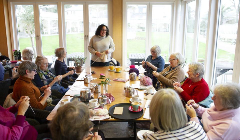 a woman sharing ideas with a knitting group in a community space