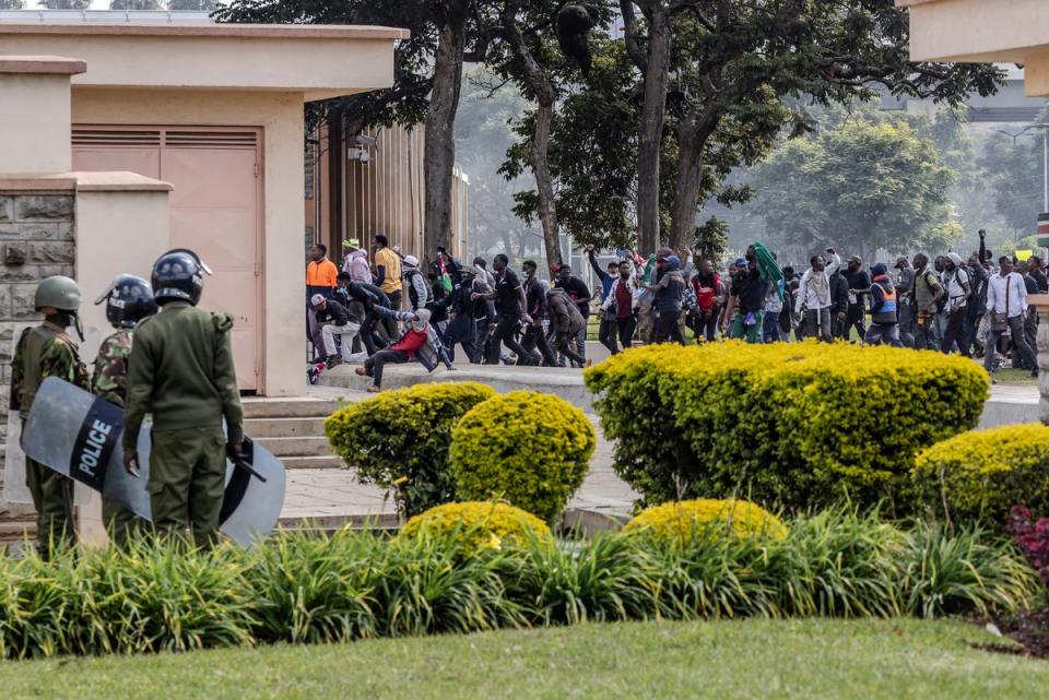 Protesters run inside the Kenyan parliament as police look on (AFP via Getty)