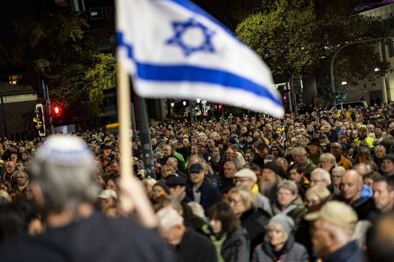 Una persona sostiene una bandera israelí mientras la gente asiste a una manifestación por la paz en Essen, Alemania, el domingo 12 de noviembre de 2023.
