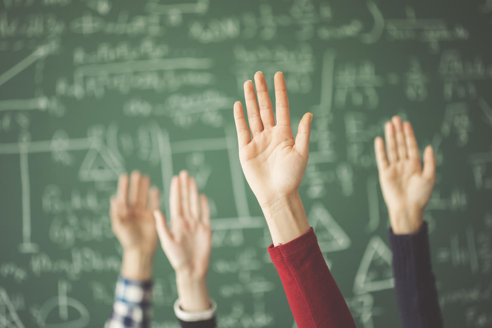 Hands are raised in front of a blackboard.