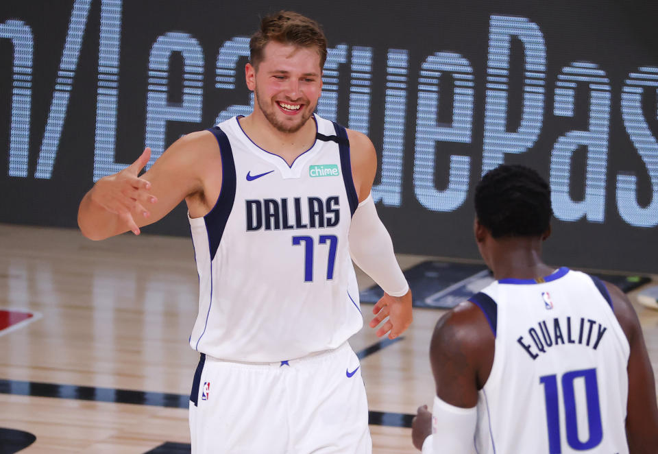 Dallas Mavericks' Luka Doncic (77) celebrates a three point-basket with teammate Dorian Finney-Smith (10) during the fourth quarter of an NBA basketball game against the Milwaukee Bucks, Saturday, Aug. 8, 2020, in Lake Buena Vista, Fla. (Kevin C. Cox/Pool Photo via AP)