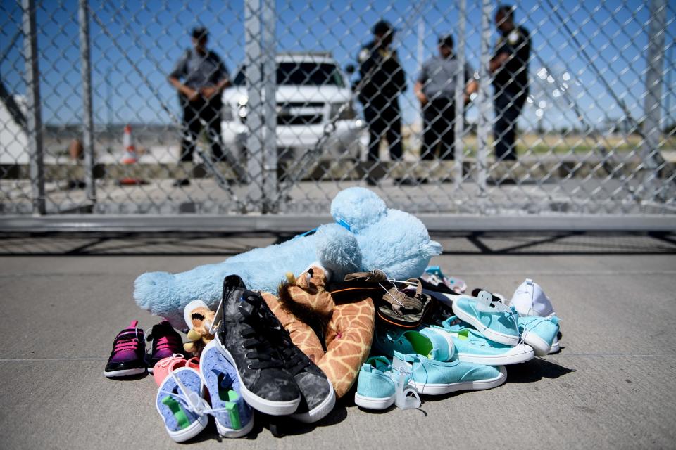 Security personal stand before shoes and toys left at the Tornillo (Texas) Port of Entry where minors crossing the border without proper papers have been housed after being separated from.