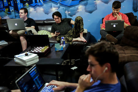 Zander Dejah (2nd L), 25, who works as a Virtual Reality engineer, Nick Olszowy (C), 25, a software engineer and Andrew Bresee, 26, a software engineer, all who are residents of The Negev tech house, use their electronics during a Sunday "family" dinner in San Francisco, California, U.S. October 30, 2016.