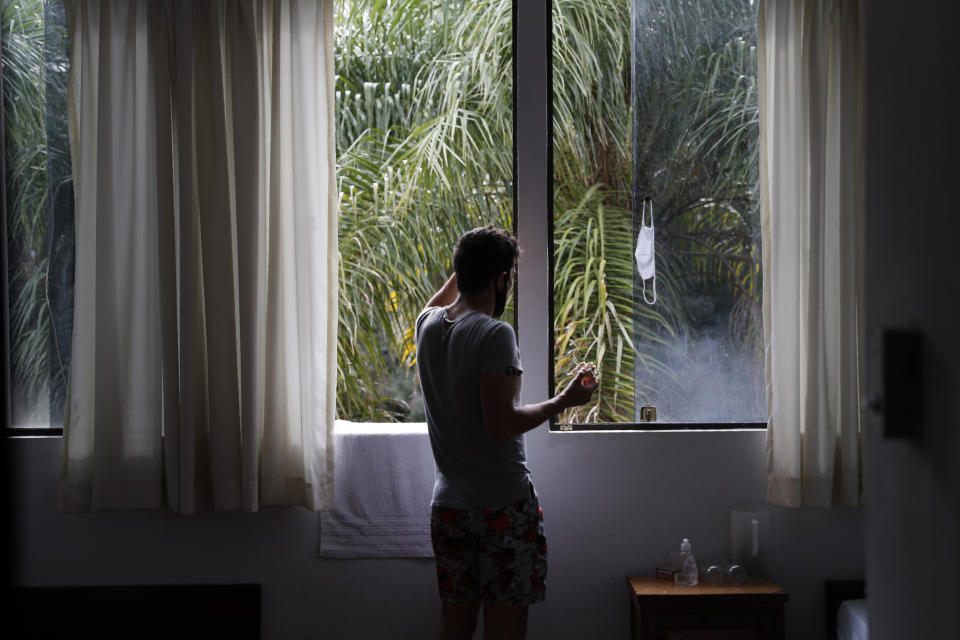 A youth eating an apple looks at the garden of a religious institution being used as a government-run shelter where citizens returning home are required by law to quarantine for two weeks and pass two consecutive COVID-19 tests, as a preventive measure amid the COVID-19 pandemic near Asuncion, Paraguay, Thursday, June 18, 2020. As nearby nations grapple with uncontrolled spread of the novel coronavirus, the small, poor, landlocked nation of Paraguay appears to be controlling the disease, with just a few thousand confirmed cases and a few dozen deaths. (AP Photo/Jorge Saenz)