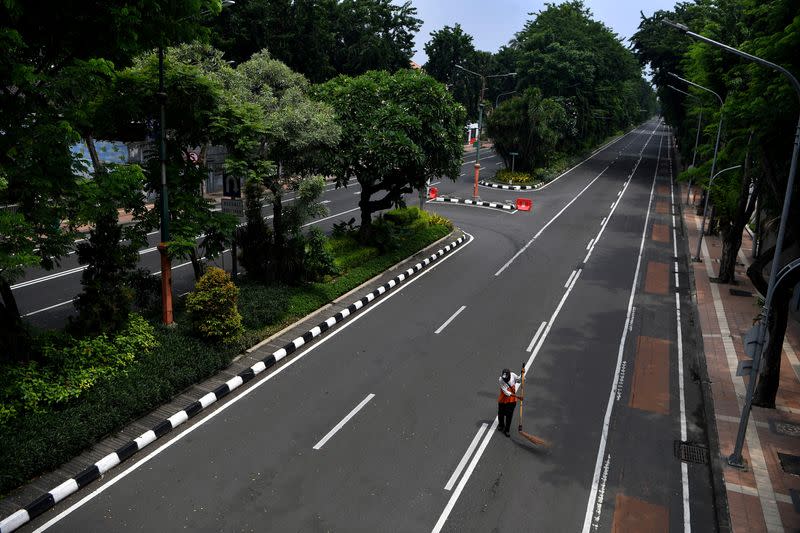A worker sweeps the road closed amid the spread of coronavirus disease (COVID-19) in Surabaya
