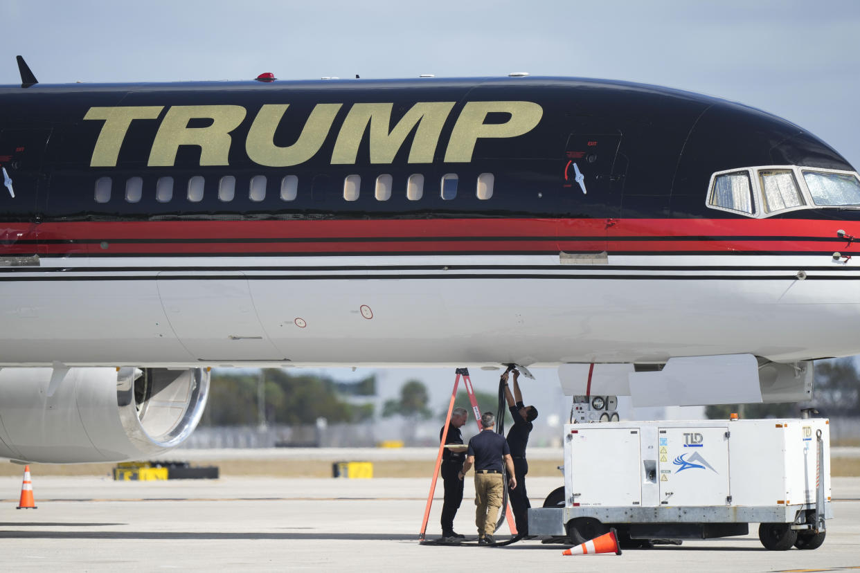 Maintenance personnel are seen working on a ground power unit underneath the personal airplane of former President Donald Trump at Palm Beach International Airport in West Palm Beach, Fla., Wednesday, March 22, 2023. (AP Photo/Gerald Herbert)