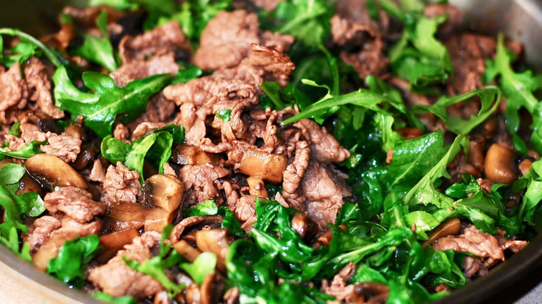 Close-up of cooked beef and greens in pan