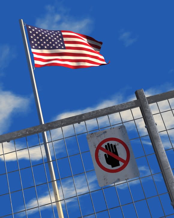 U.S. flag behind a metal fence with a keep-out sign posted on it.