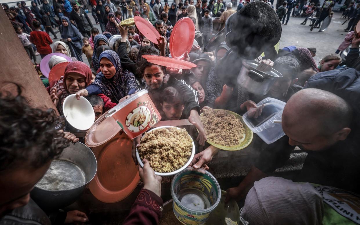 Displaced Palestinians gather to receive food at a government school in Rafah in the southern Gaza Strip