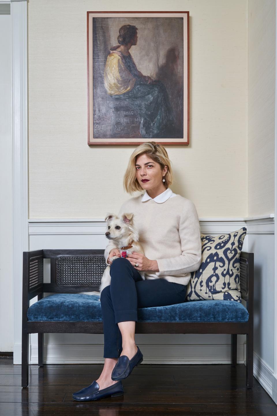 Blair and her pup, Pippa, relax in the in a corner of the living room. Interior designer Bryan Wark gave new life to an antique cane bench with a cobalt velvet cushion. Then he topped it with an ikat pillow he made.